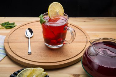 Çay fincanının içinde çay demlik kaşığının yanında limon ve limon merhemi. Yuvarlak bir tezgahın üstünde..