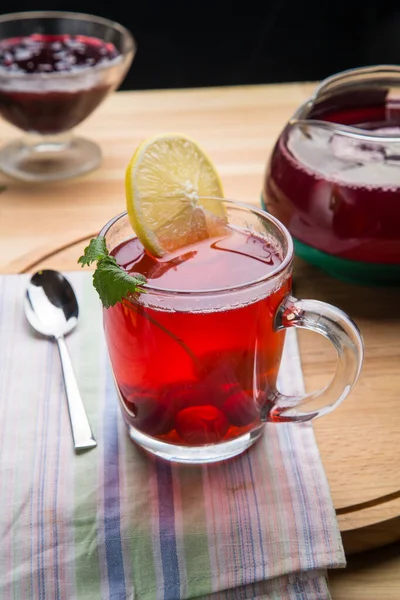 Limonlu bardakta çilek çayı peçetenin üstünde kaşığın yanında..