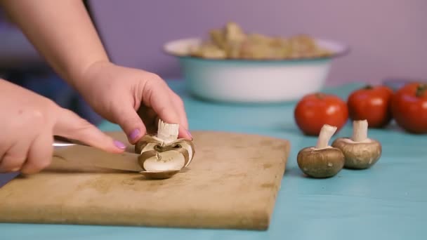 Una mano femminile su una tavola di legno taglia funghi con un coltello — Video Stock