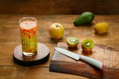 Ahşap masada meyveler ve bir bardak meyve püresi var.