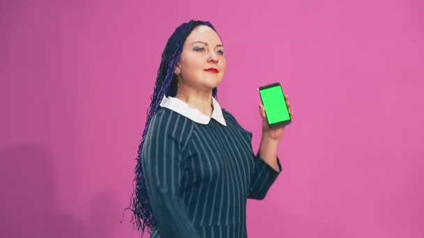 带着蓝色非洲辫子的时髦的黑发女郎手拿着手机在绿色的屏幕上跳舞 — 图库视频影像