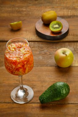 Bir bardak taze kivi elmalı smoothie, ahşap bir masada, yanında da elma avokadosu duruyor. Dikey fotoğraf