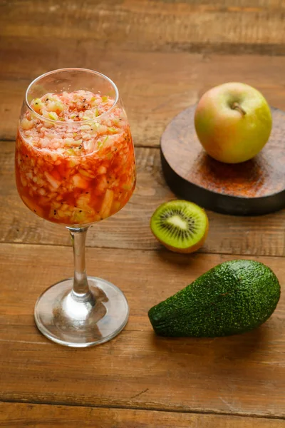 Bir bardak taze kivi elmalı smoothie, ahşap bir masada, yanında da elma avokadosu duruyor. Dikey fotoğraf