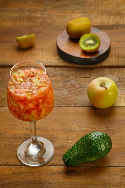 Bir bardak taze kivi elmalı smoothie, ahşap bir masada, yanında da elma avokadosu duruyor. Dikey fotoğraf