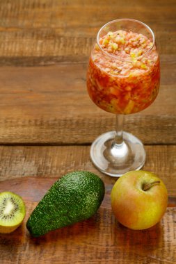 Elmalı kivi kokteylinin yanında, ahşap bir masanın üzerinde bir bardak kivi kokteyli. Dikey fotoğraf