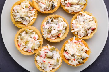 Siyah arka planda beyaz tabakta salatalı turta. Yatay fotoğraf