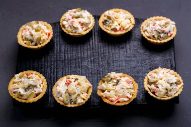 Ananaslı salata turtaları ve gri beton arka planda siyah tahta üzerinde karidesler. Yatay fotoğraf