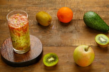 Bir bardak kivi elmalı kokteyl içeceği kivi elmalı avokado avokado yatay fotoğrafının yanındaki ahşap masada.