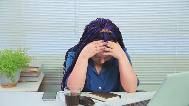 在办公室里戴着蓝色非洲辫子背对着电脑前的窗户的女人累了 用手擦着威士忌 中期计划 — 图库视频影像