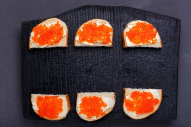 Tereyağlı ve kırmızı havyarlı köfteler gri beton arka plan fotokopi alanındaki siyah tahtaya serilmişti. Yatay fotoğraf