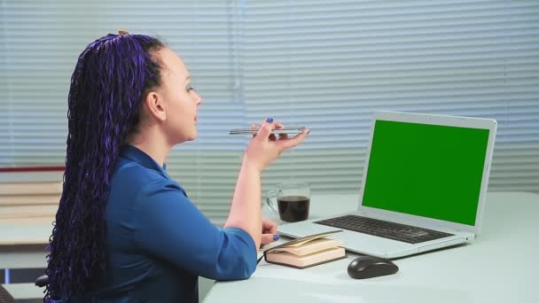 在办公室里拿着蓝色非洲辫子的女人在电脑前的绿色屏幕上通过电话交谈 中期计划 — 图库视频影像