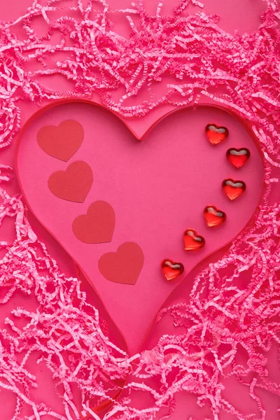 Sobre un fondo rosa, decoración del día de San Valentín de un corazón volumétrico hecho de papel y guijarros y cintas. —  Fotos de Stock