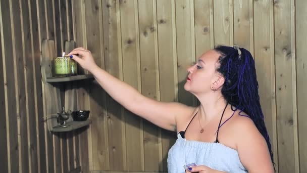 Μια γυναίκα σε ένα μπάνιο σε μια πετσέτα ανάβει κεριά για χαλάρωση — Αρχείο Βίντεο
