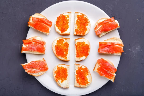 Borstar med smör och röd kaviar och öring på en vit tallrik. — Stockfoto
