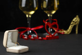 Na černém pozadí, krabice s prstenem v pozadí brýle se šampaňským a suvenýry.