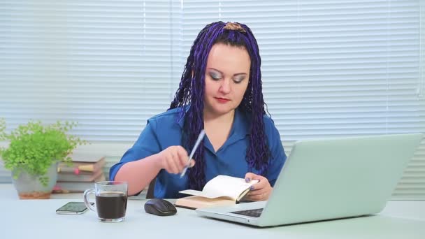 Mulher com tranças afro azuis no escritório trabalha em um computador com um notebook — Vídeo de Stock