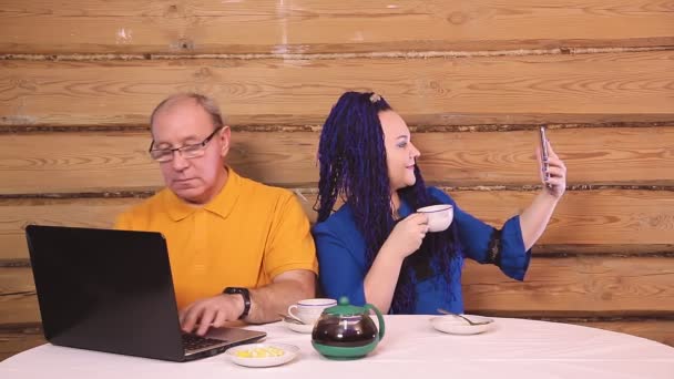 テーブルの上で結婚式を挙げた夫婦はパソコンで仕事をし女はお茶を飲んで — ストック動画