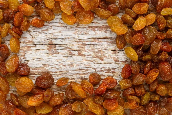 Dried sweet golden raisins on wooden background copy place.