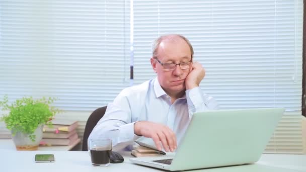 Um homem com óculos no escritório no computador trabalha com projetos — Vídeo de Stock