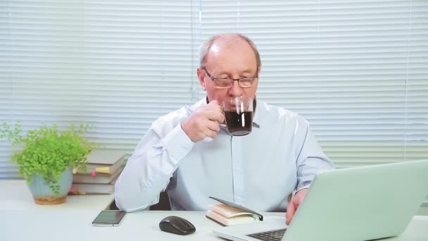 Männliche Führungskraft mit Brille im Büro am Computer arbeitet und trinkt Kaffee — Stockvideo