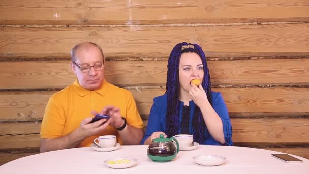 Una coppia sposata a tavola a casa un uomo e una donna con una donna dai capelli neri bevono tè con cupcake — Video Stock