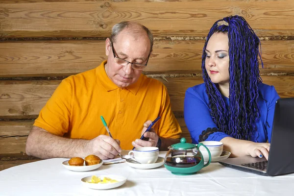 Одружена пара чоловік в окулярах і жінка з синіми афро косами за столом працюють за комп'ютером . — стокове фото