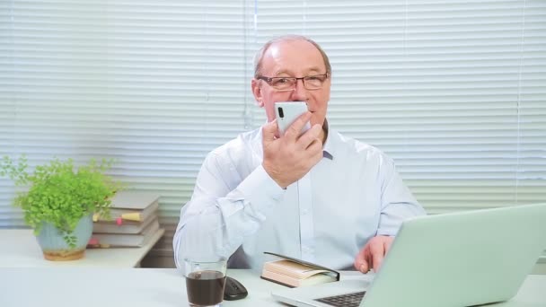 Bilgisayarın başındaki adam telefonla konuşuyor ve çalışıyor. — Stok video