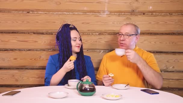 Evdeki masada oturan evli bir çift. Bir adam ve bir kadın, Afro saçlı bir kadınla birlikte çöreklerle çay içiyorlar. — Stok video