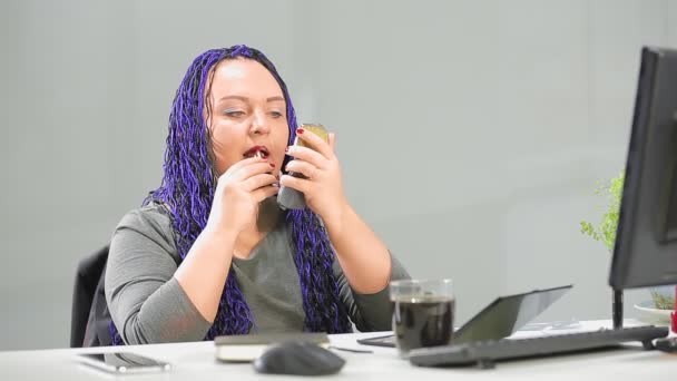 Uma mulher judia em um escritório com um penteado afro azul pinta seus lábios vermelhos olhando para um pequeno espelho no início do dia de trabalho — Vídeo de Stock