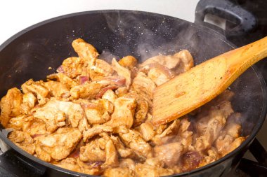 Soya soslu tavuk fileto ve limon suyu kızartma tavasında ahşap bir spatulayı karıştırıyor..