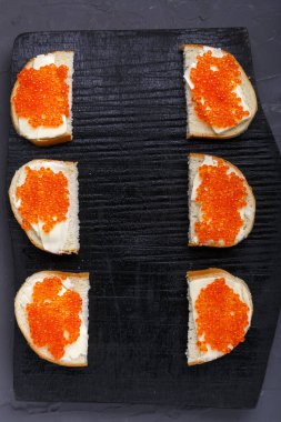 Tereyağı ve kırmızı havyarlı köfteler gri beton arka plan fotokopi alanı üzerine siyah bir tahta üzerine serilmişti..