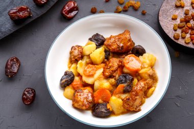 Bir tabak yahudi mutfağı. İçinde hurma, havuç ve hindi eti var. Beyaz bir tabakta..