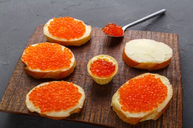 Yağ, kırmızı havyar ve havyarlı bir kaşık ile kahverengi bir tahta üzerinde havyar. Yatay fotoğraf