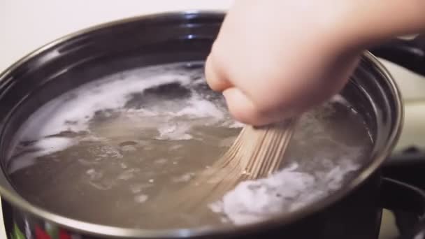 女性の手は鍋の沸騰水にスパゲティを下げる 中期計画 — ストック動画
