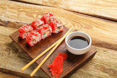 Karides salatalığı ve tobiko havyarla yuvarlan ve tahta zemindeki bir sos kasesinde soya sosu ve tahtaya yapış. Yatay fotoğraf