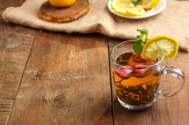 Bardakta yeşil çay, nane aromalı ve limonlu, peçeteli bir tabakta, limonlu. Yatay fotoğraf