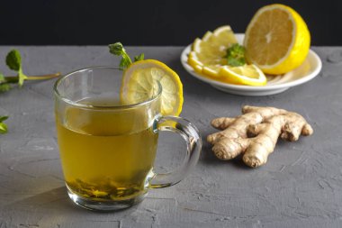 Zencefilli içecek, ballı nane ve limonlu, zencefil kökü ve limonlu bardakta beton arka planda..