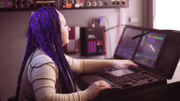Illustrativ ledare Kvinna ljusdesigner med blå afrocos på Grand Mas-konsolen arbetar med ljusprogrammering — Stockvideo
