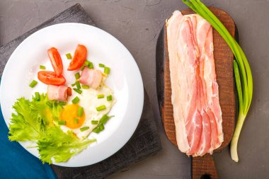 Domatesli ve yeşil soğanlı sahanda yumurta ve bir sıra doğranmış pastırma, domates ve soğanlı gri beton kaplama..