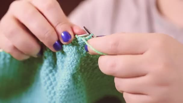 Las manos de las mujeres sostienen agujas de punto y tejen de lana ligera con un patrón simple — Vídeo de stock