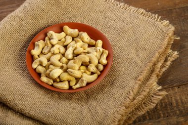 Tahta bir masada çuval bezi üzerinde killi bir kasede fındık..