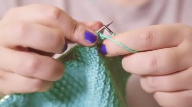Kadınların elleri basit bir desenle örgü iğnelerini ve yün örgülerini tutarlar.