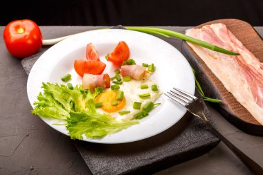 Yağda yumurta, domuz pastırması, domates ve yeşil soğanla süslenmiş pastırma, domates ve soğan dilimlenmiş..