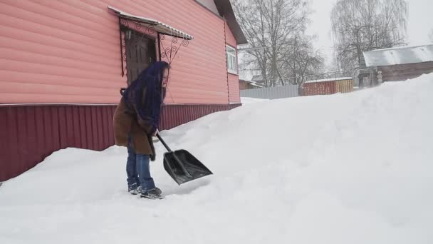 彼女の家の庭に雪の後に雪を削除します。彼女は彼女の家の庭に雪を削除します。 — ストック動画