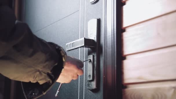 De man steekt de sleutel in het sleutelgat, draait zich om en opent de deur en de man komt binnen — Stockvideo
