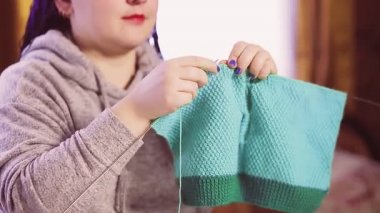 Mavi afro saçlı, yün kazak ören bir kadın.