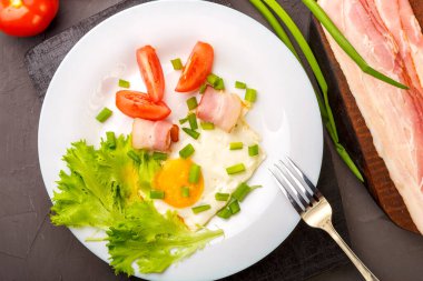 Domatesli ve yeşil soğanlı sahanda yumurta ve bir sıra doğranmış pastırma, domates ve soğanlı gri beton kaplama..