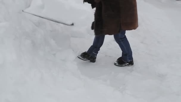 シャベル付きの暖かいコートの女性は雪の後に雪を削除します. — ストック動画