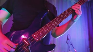 Neon ışıklı bir adam bir konserde yüzsüz gitar çalıyor.