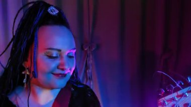 Afro saç stili bir kadın müzisyen bir konserde elektro gitar çalar. Dikey Panorama